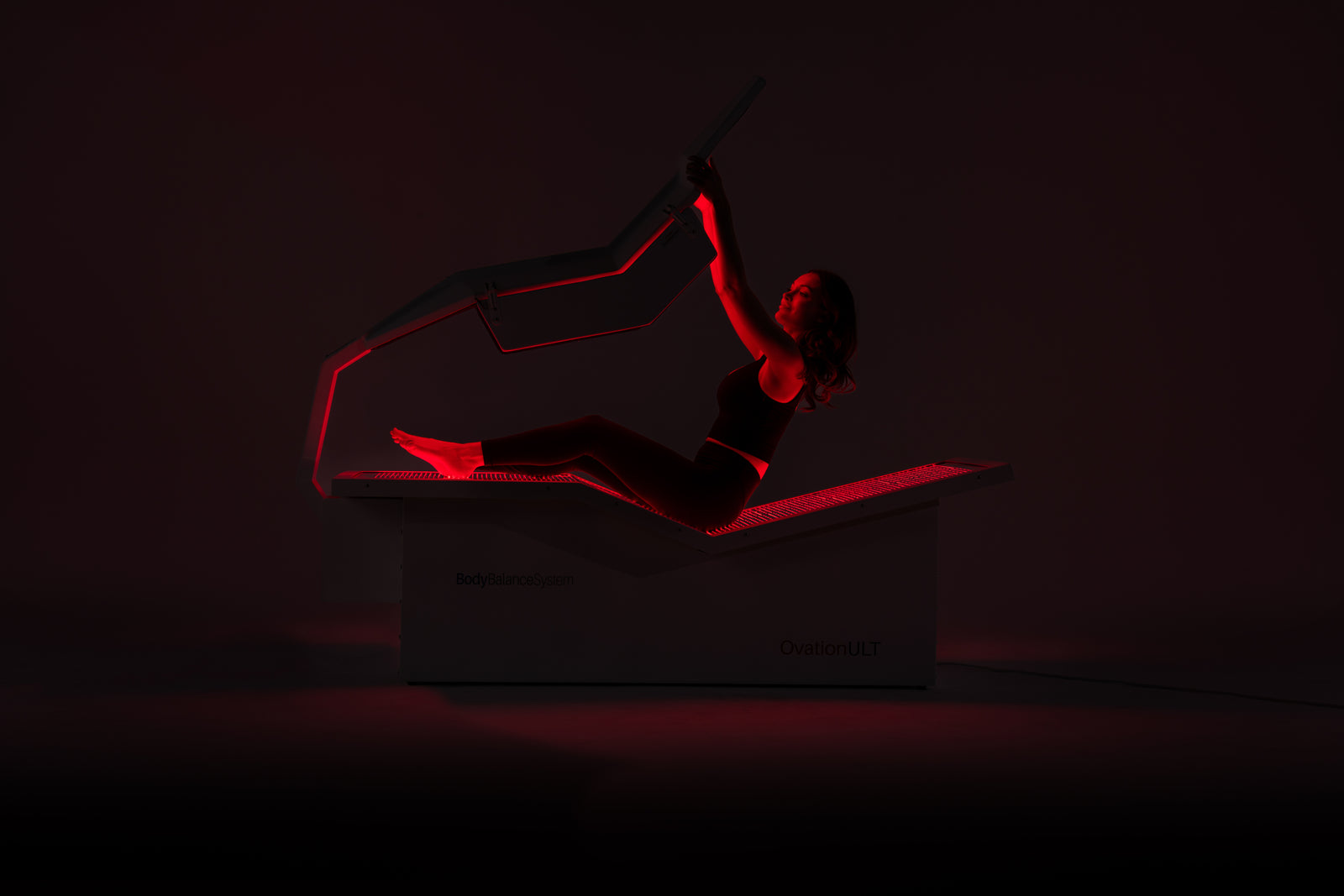 Person in silhouette performing a yoga pose on a dark background