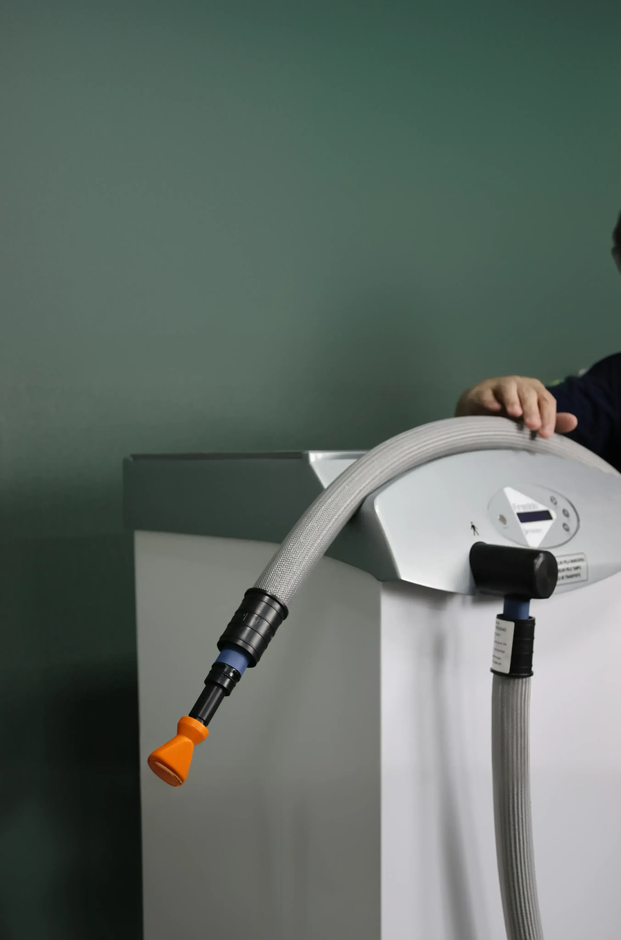 Clinician holding a hose attached to Freddo Aesthetic Skin Cooling chiller machine with a green background