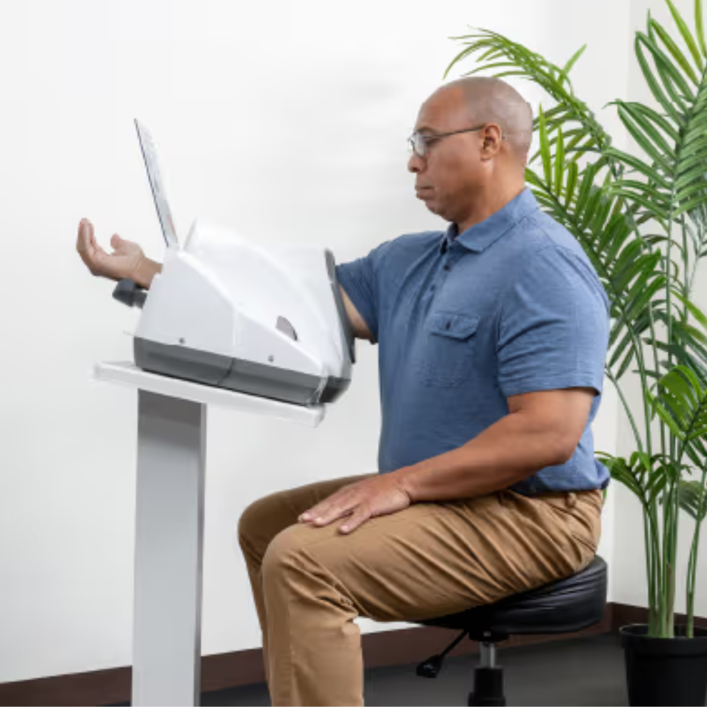 A man using an InBody blood pressure kiosk in an office setting with a plant in the background.