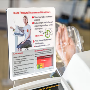 Blood pressure measurement guidelines are displayed on a chart while a person uses an InBody Blood Pressure Kiosk