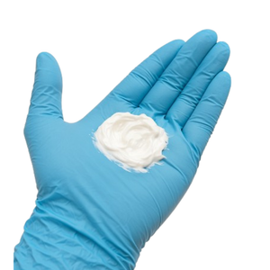 Blue glove holding Neuro Med BLT Cream against a light gray background