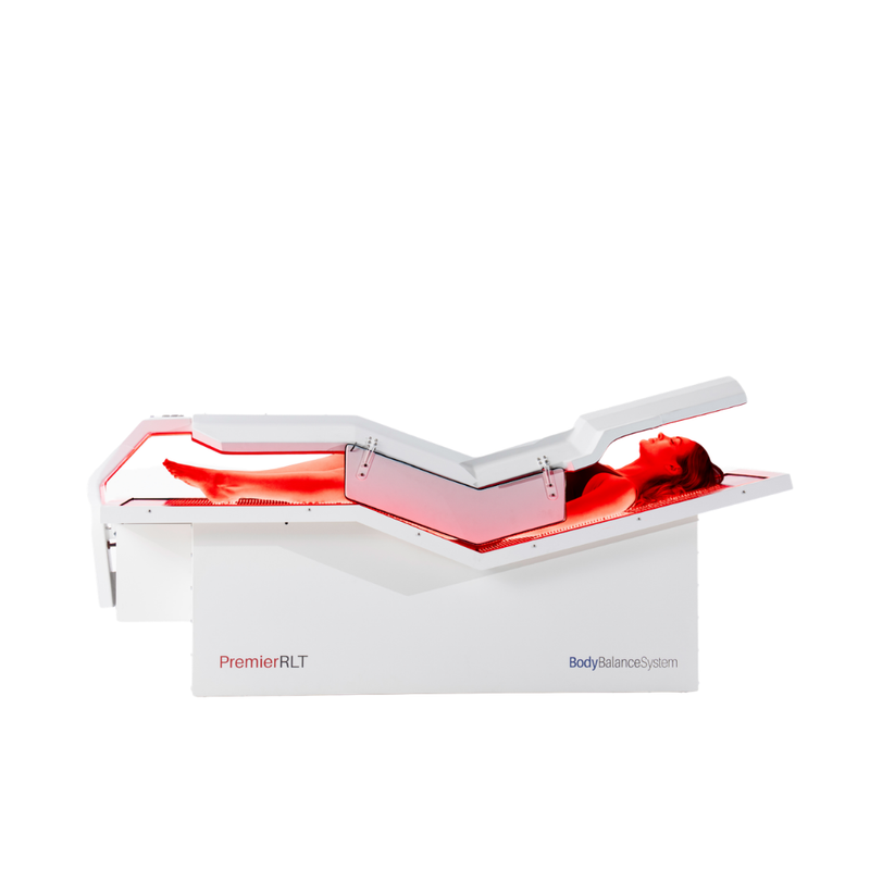 Body Balance System Premier RLT red light therapy bed on a white background with lights on and model.
